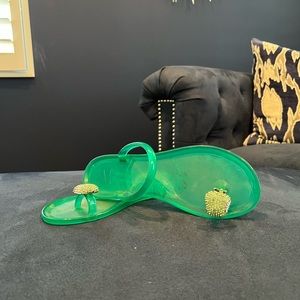 Green sandals with a butterfly design on the toe.